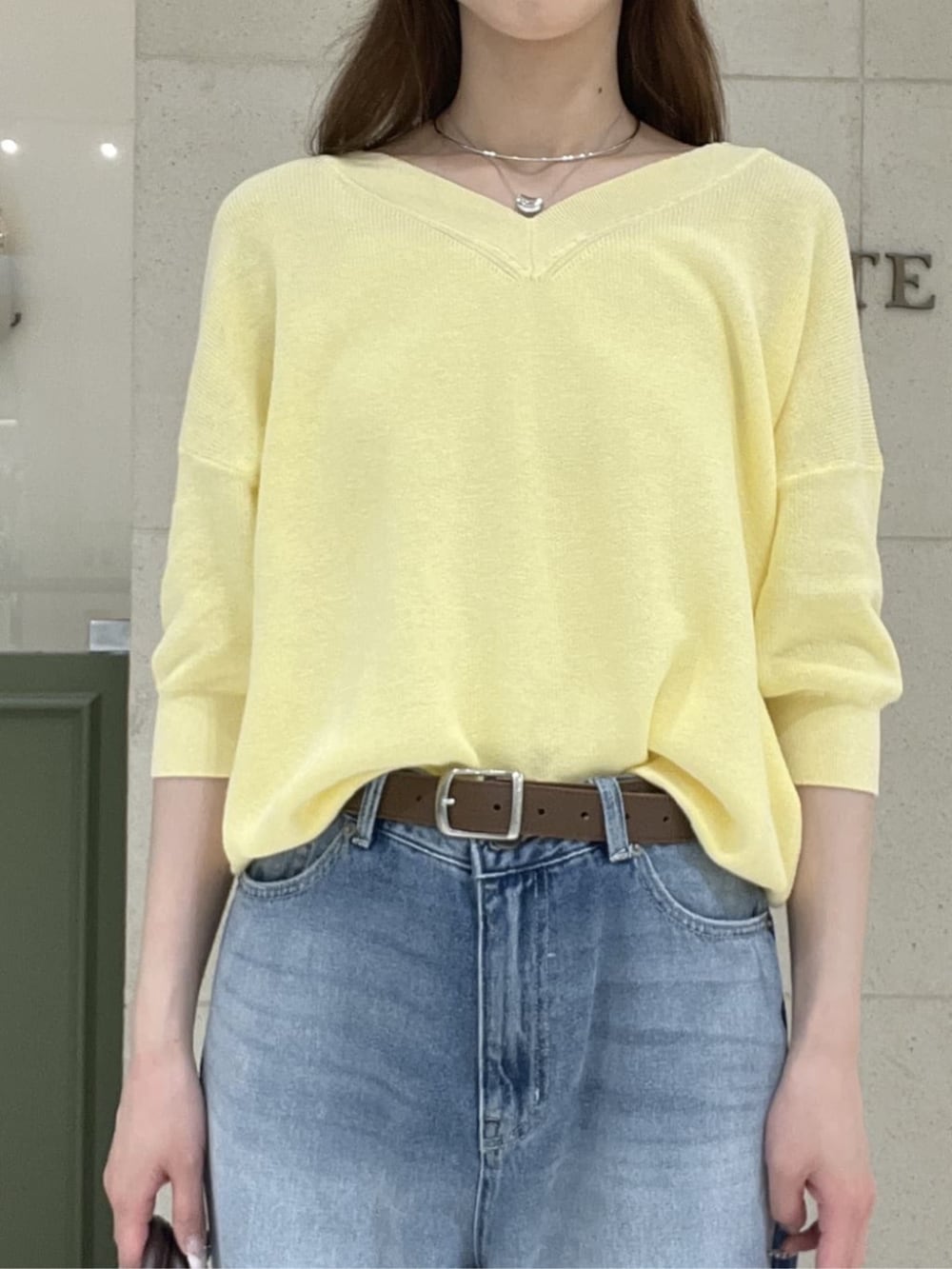 ブラウン系のボストンバッグ、イエロー系のニット/セーター、ブルー系のデニムパンツを着用したレディースの春コーディネートの4枚目の写真