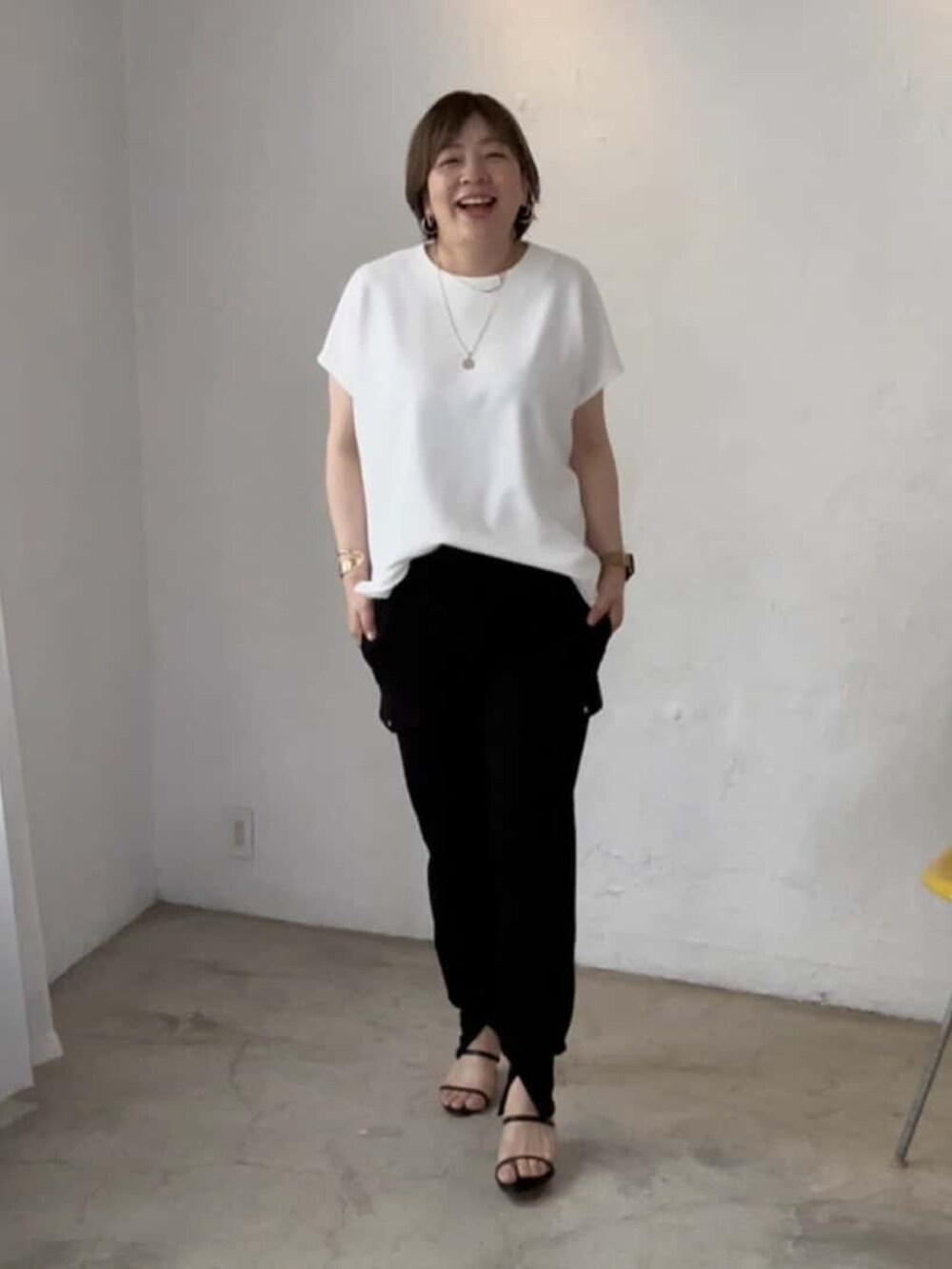 ブラック系のその他パンツ、ブラック系のサンダル、ホワイト系のTシャツ/カットソーを着用したレディースの春コーディネートの3枚目の写真