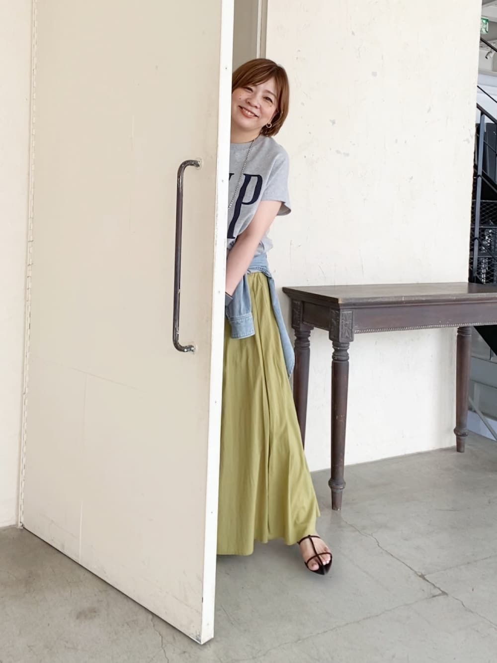 グレー系のTシャツ/カットソー、グリーン系のスカート、ブラック系のハンドバッグを着用したレディースの夏コーディネートの2枚目の写真