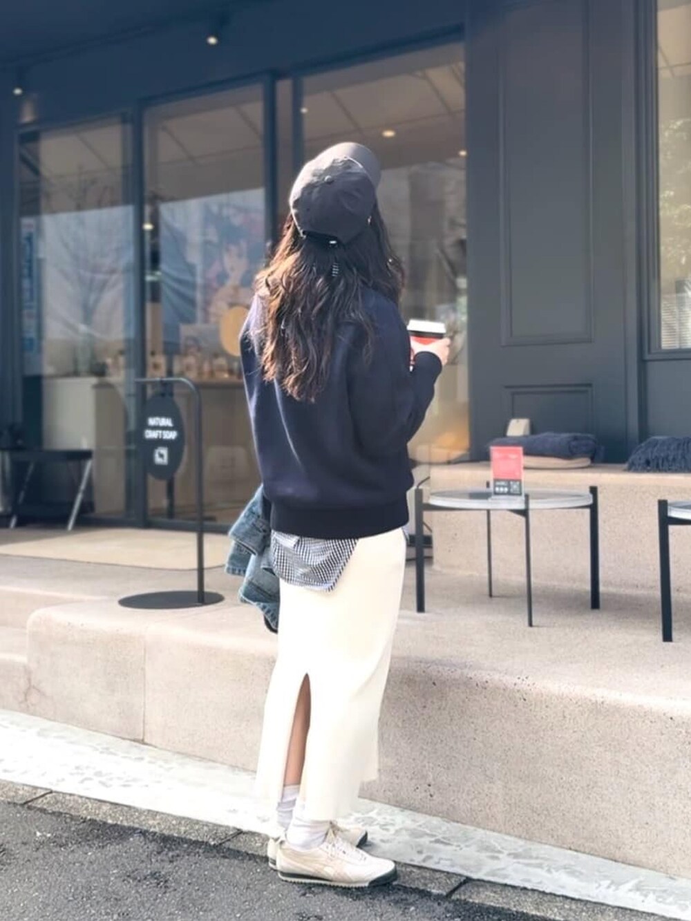 ブルー系のニット/セーター、ブラック系のシャツ/ブラウス、ホワイト系のスカートを着用したレディースの春コーディネートの3枚目の写真