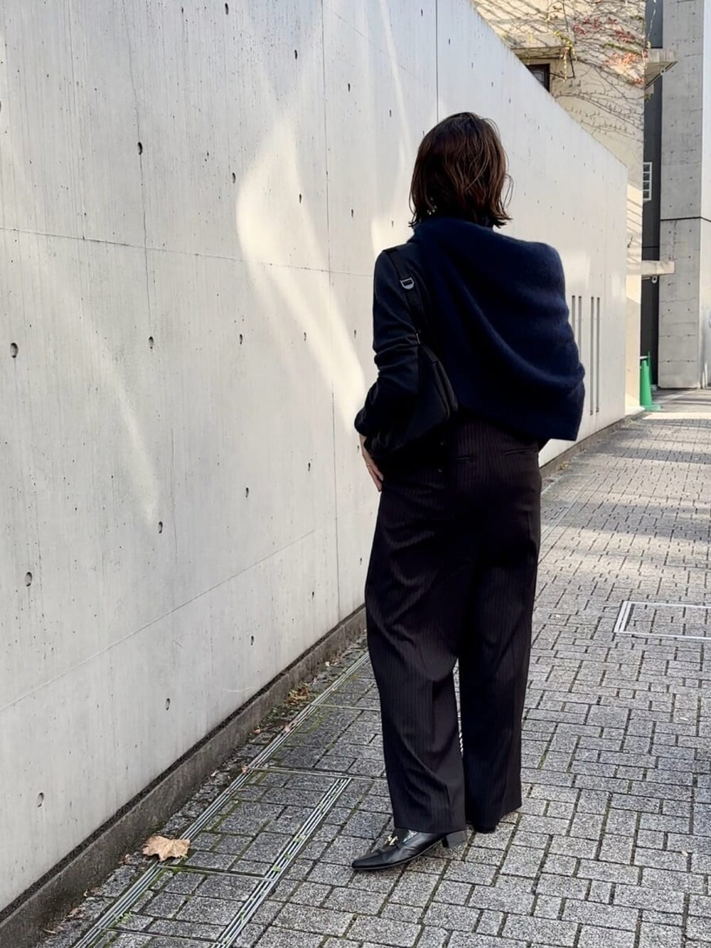 ブルー系のニット/セーター、ブラック系のスラックス、ブラック系のローファーを着用したレディースの冬コーディネートの5枚目の写真