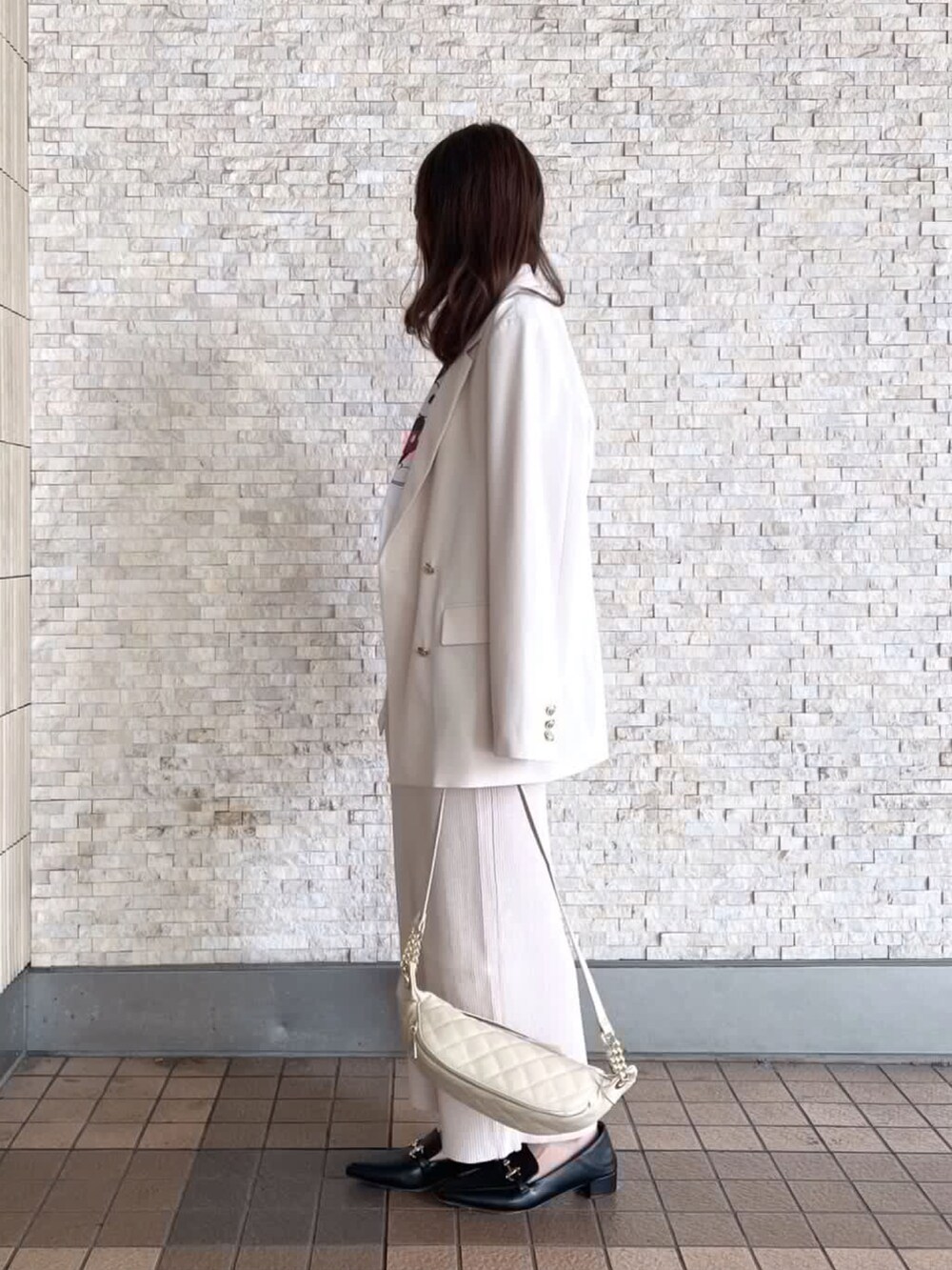 ベージュ系のスカート、ブラック系のローファーを着用したレディースの秋コーディネートの2枚目の写真