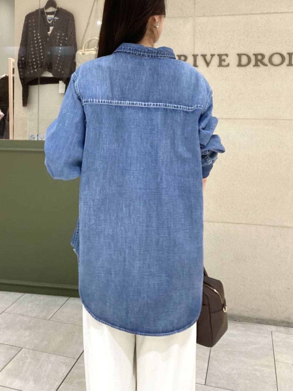 ホワイト系のスラックス、ブルー系のシャツ/ブラウス、ブラウン系のボストンバッグを着用したレディースの春コーディネートの6枚目の写真