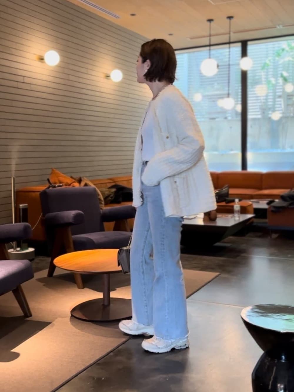 ホワイト系のカーディガン/ボレロ、ブルー系のデニムパンツ、ブラウン系のショルダーバッグを着用したレディースの冬コーディネートの2枚目の写真