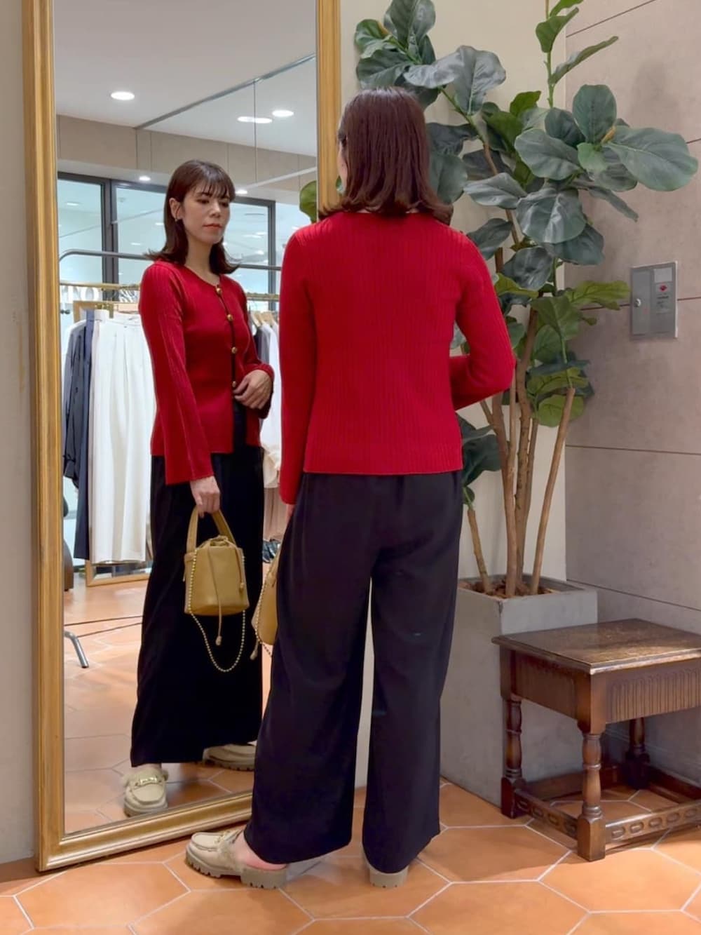 レッド系のカーディガン/ボレロ、ブラック系のスラックス、イエロー系のハンドバッグを着用したレディースの秋コーディネートの3枚目の写真