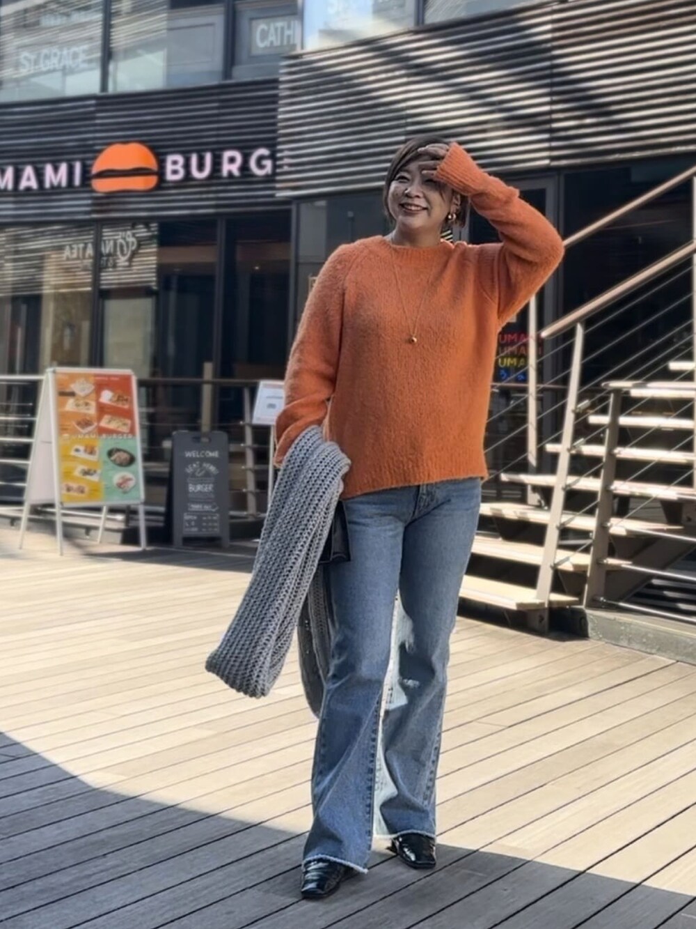 オレンジ系のニット/セーター、ブルー系のデニムパンツを着用したレディースの冬コーディネートの2枚目の写真