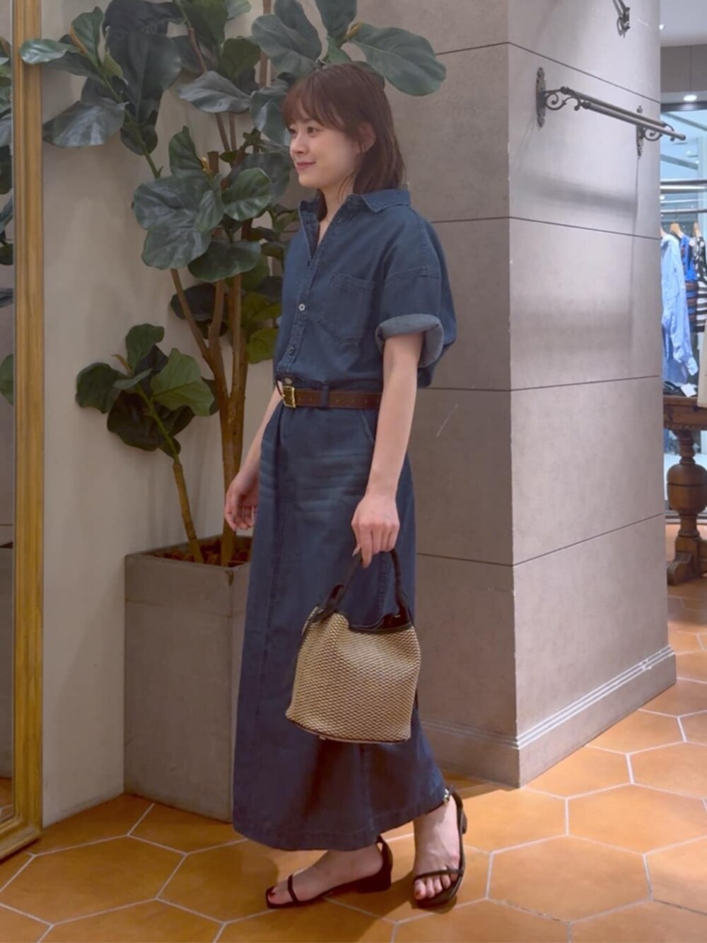 ブラック系のハンドバッグ、ブルー系のワンピース、ゴールド系のネックレスを着用したレディースの夏コーディネートの2枚目の写真