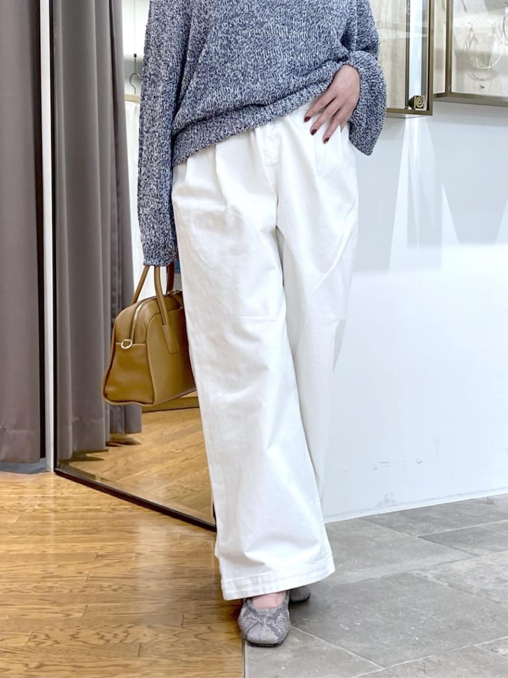 イエロー系のボストンバッグ、ホワイト系のデニムパンツ、ブルー系のニット/セーターを着用したレディースの春コーディネートの4枚目の写真