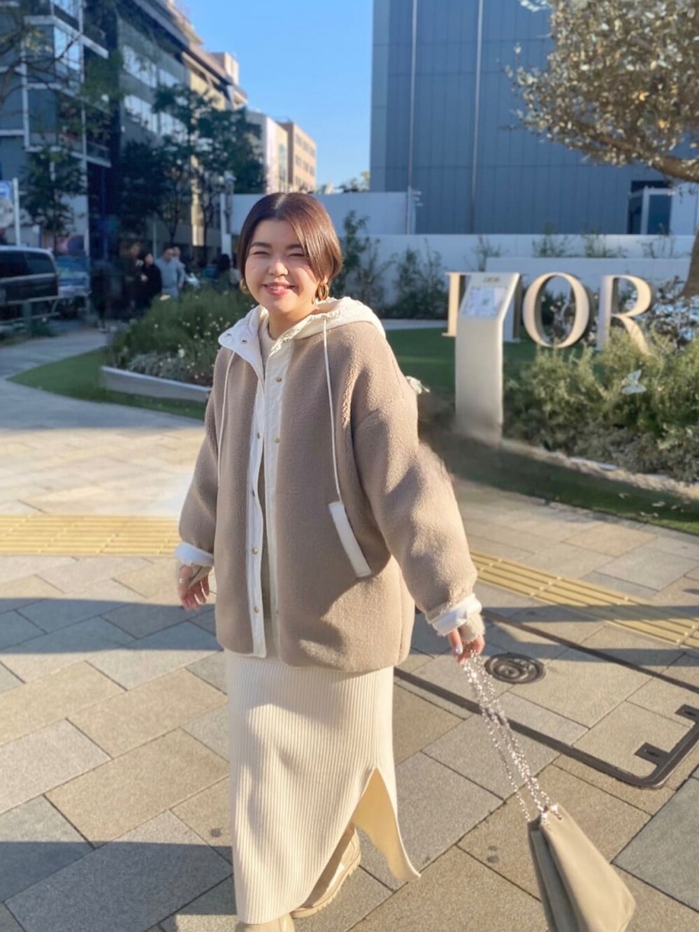 ベージュ系のその他アウター、ブラック系のワンピース、ベージュ系のブーツを着用したレディースの冬コーディネートの4枚目の写真