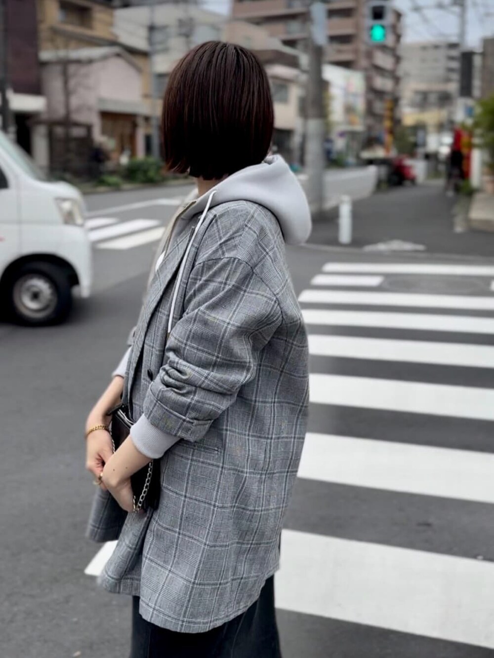 グレー系のテーラードジャケット、ブルー系のデニムスカート、ベージュ系のパーカーを着用したレディースの春コーディネートの3枚目の写真