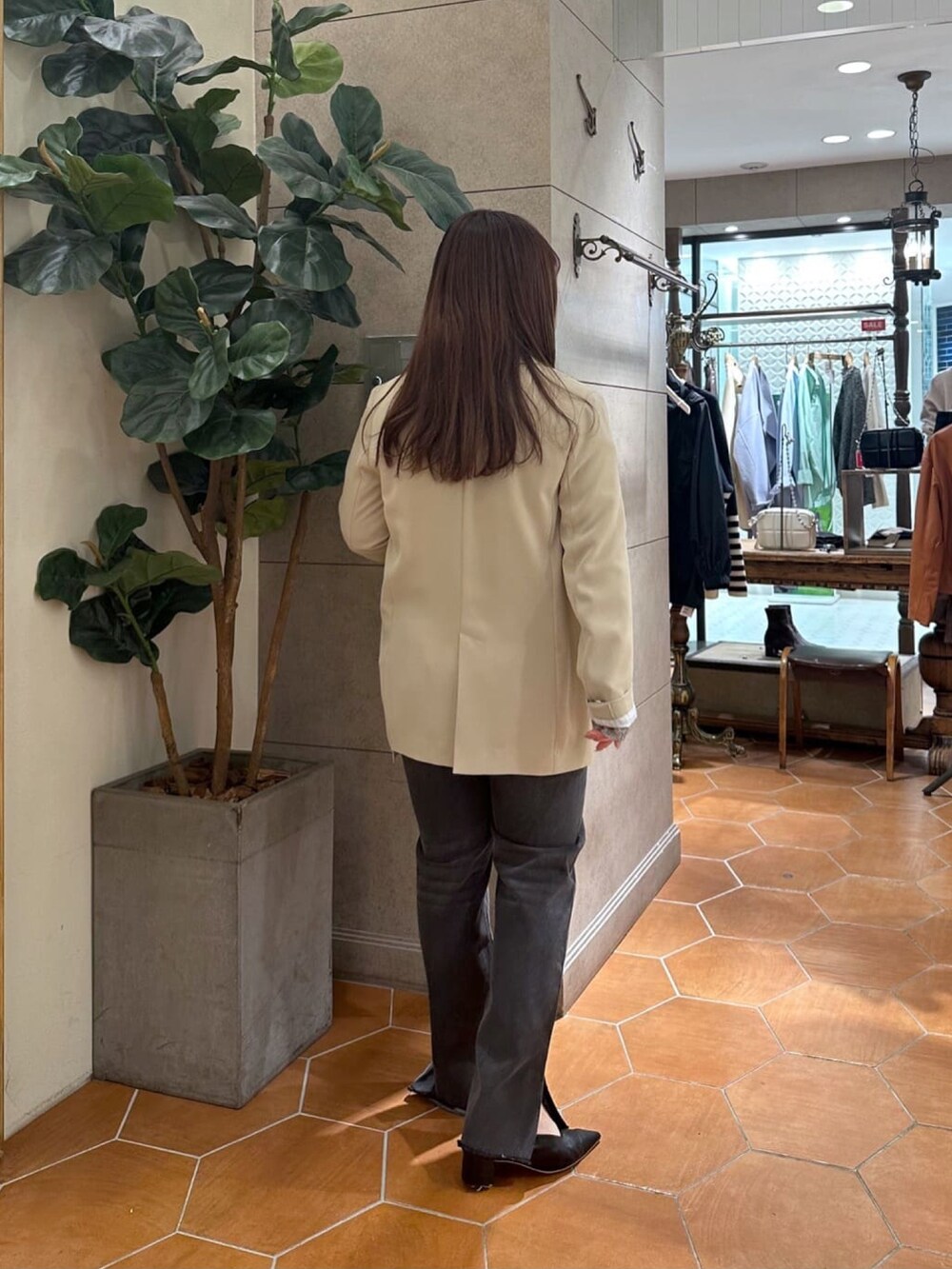 グレー系のデニムパンツ、ベージュ系のテーラードジャケット、ブラック系のパンプスを着用したレディースの冬コーディネートの3枚目の写真