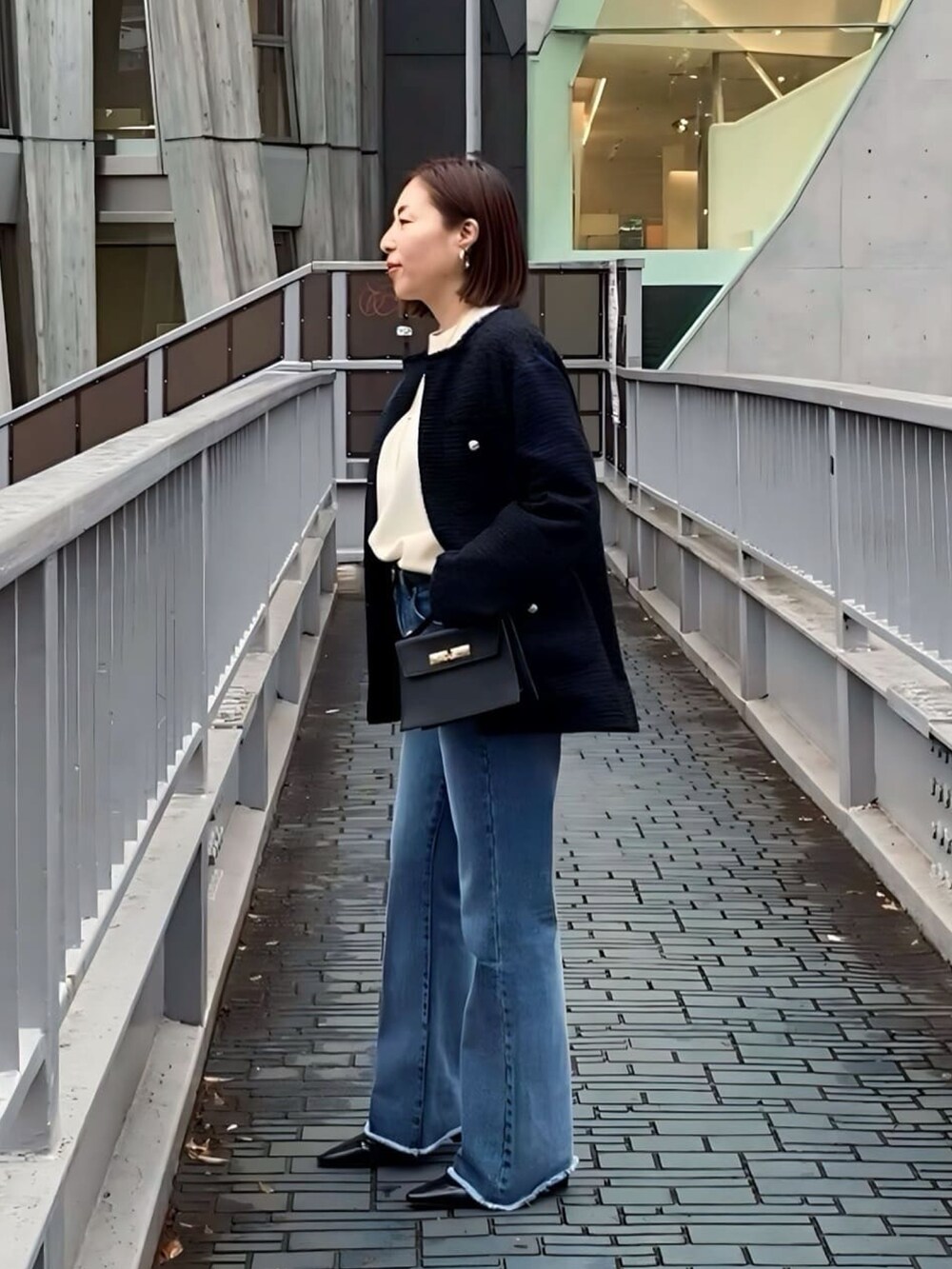 ホワイト系のニット/セーター、ブルー系のノーカラージャケット、ブラック系のハンドバッグを着用したレディースの冬コーディネートの2枚目の写真