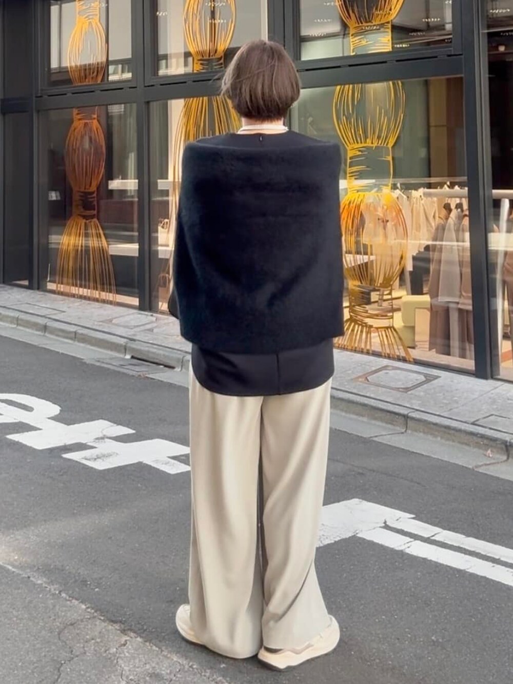 グレー系のスラックス、ブラック系のボストンバッグ、ブラック系のTシャツ/カットソーを着用したレディースの冬コーディネートの2枚目の写真