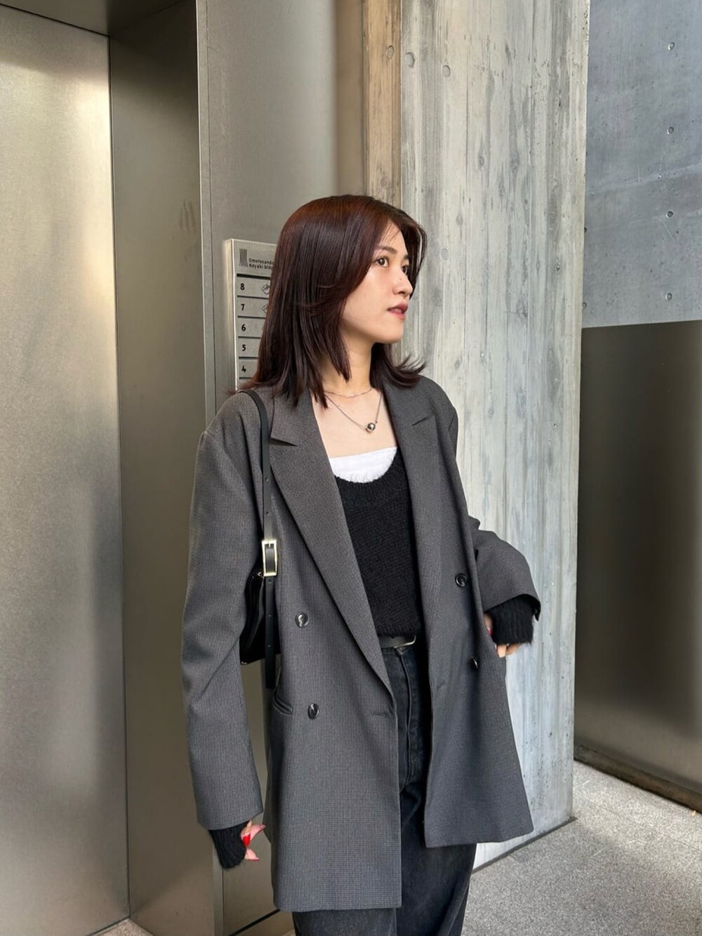 グレー系のテーラードジャケット、ブラック系のデニムパンツを着用したレディースの秋コーディネートの2枚目の写真