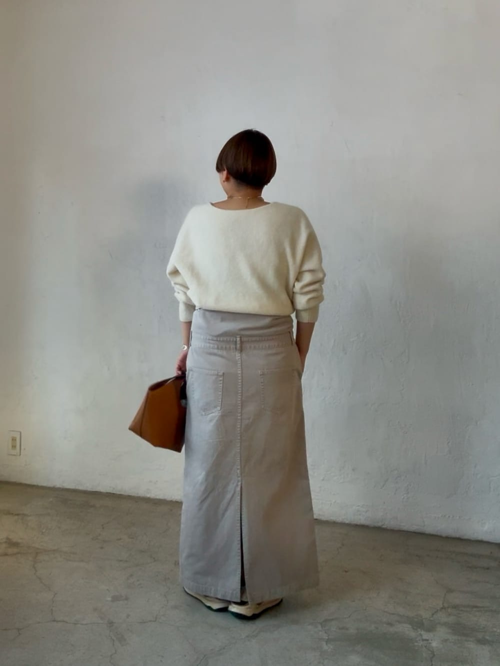 ホワイト系のニット/セーター、イエロー系のハンドバッグ、グレー系のシャツワンピースを着用したレディースの冬コーディネートの3枚目の写真