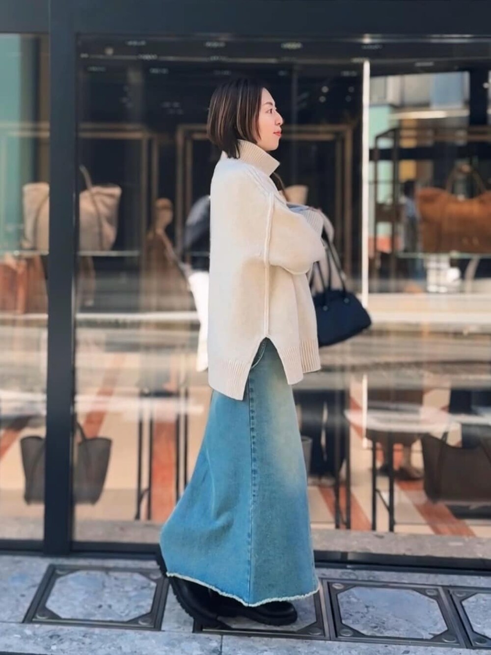 ホワイト系のニット/セーター、ブラック系のショルダーバッグ、ブルー系のデニムスカートを着用したレディースの秋コーディネートの2枚目の写真