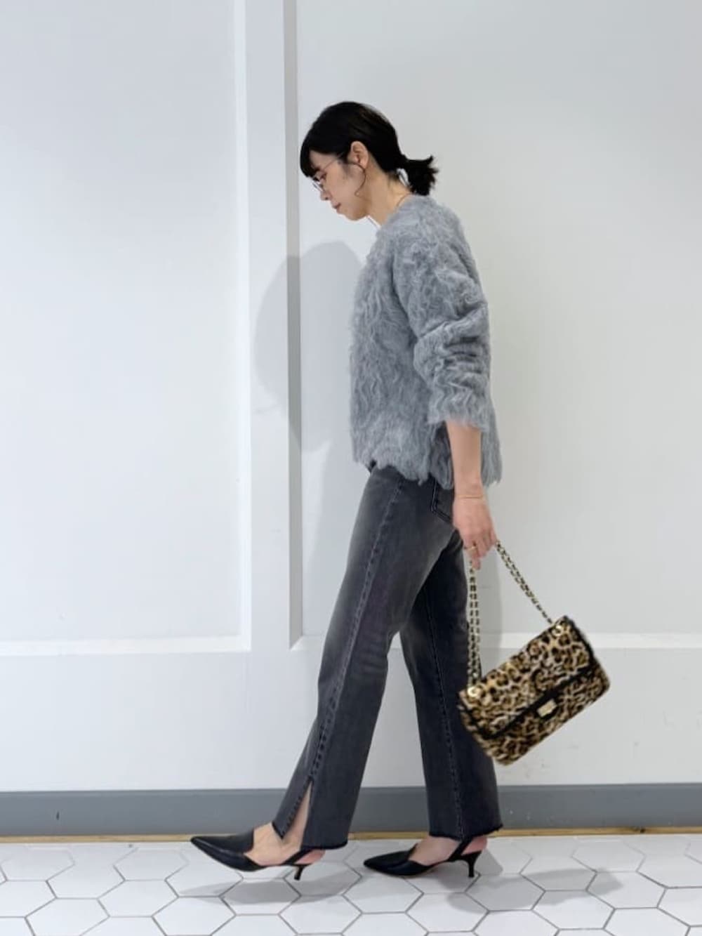 グレー系のニット/セーター、グレー系のデニムパンツ、ベージュ系のショルダーバッグを着用したレディースの秋コーディネートの2枚目の写真