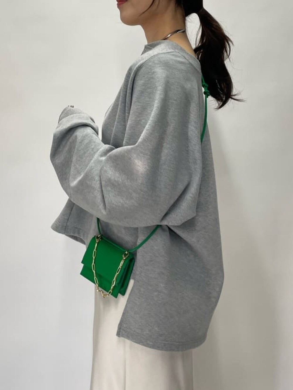 グレー系のスウェット、グリーン系のショルダーバッグ、ベージュ系のスカートを着用したレディースの冬コーディネートの5枚目の写真