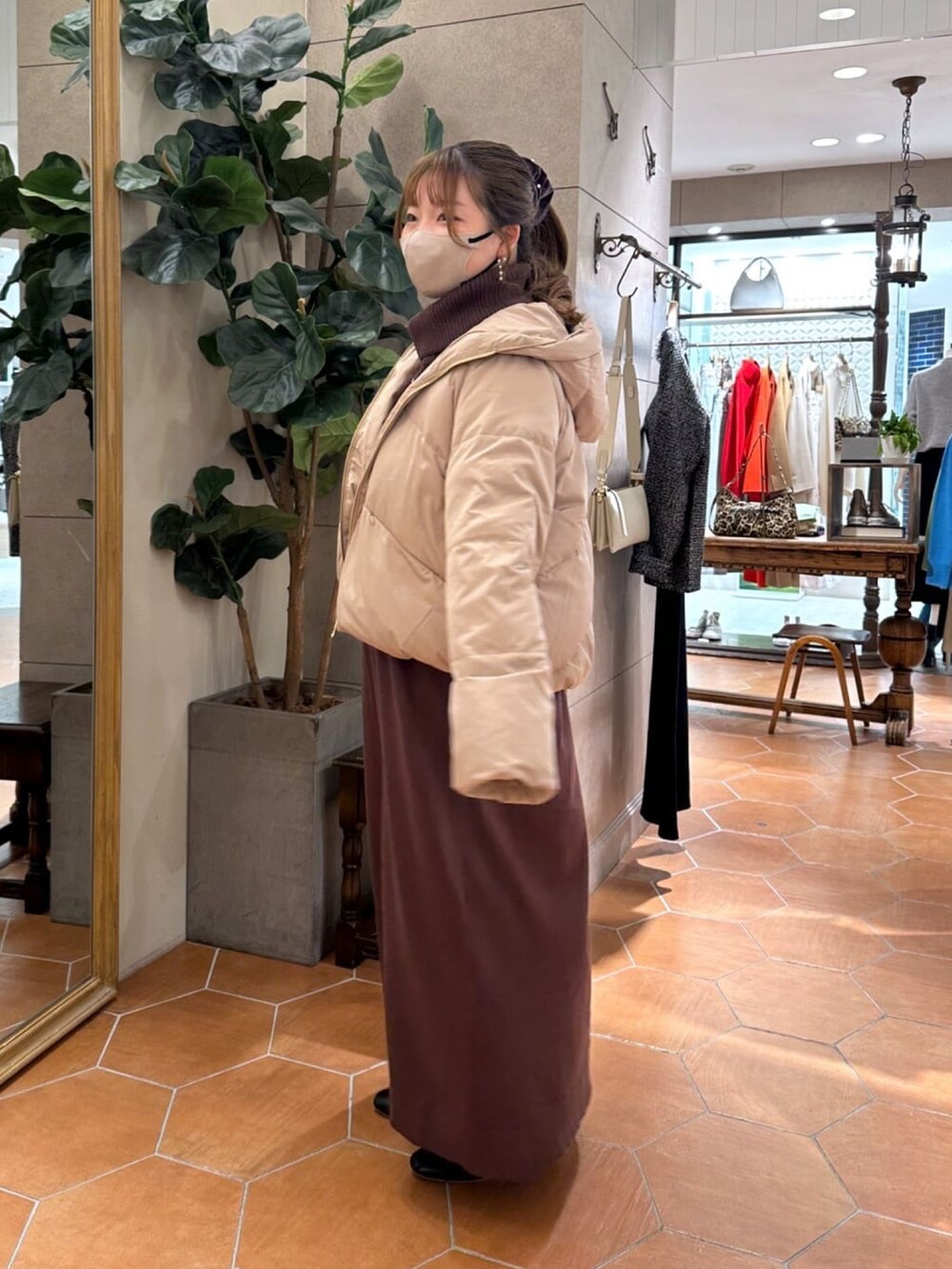 ブラウン系のワンピース、ブラック系のブーツ、ブラック系のダウンジャケット/コートを着用したレディースの冬コーディネートの2枚目の写真