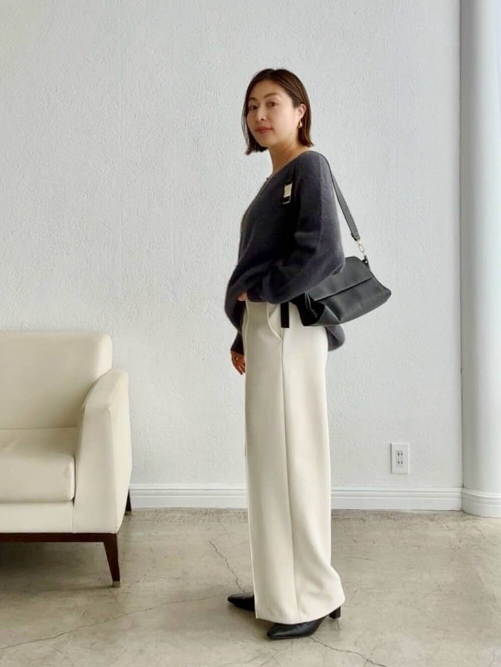 グレー系のニット/セーター、ブラック系のショルダーバッグ、ホワイト系のその他パンツを着用したレディースの秋コーディネートの2枚目の写真