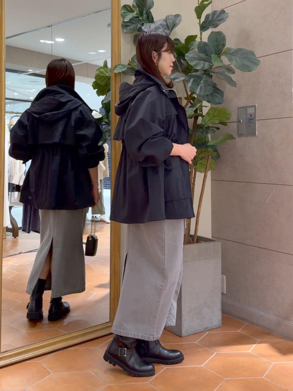 グレー系のシャツ/ブラウス、グレー系のデニムスカート、ブラック系のマウンテンパーカーを着用したレディースの冬コーディネートの3枚目の写真