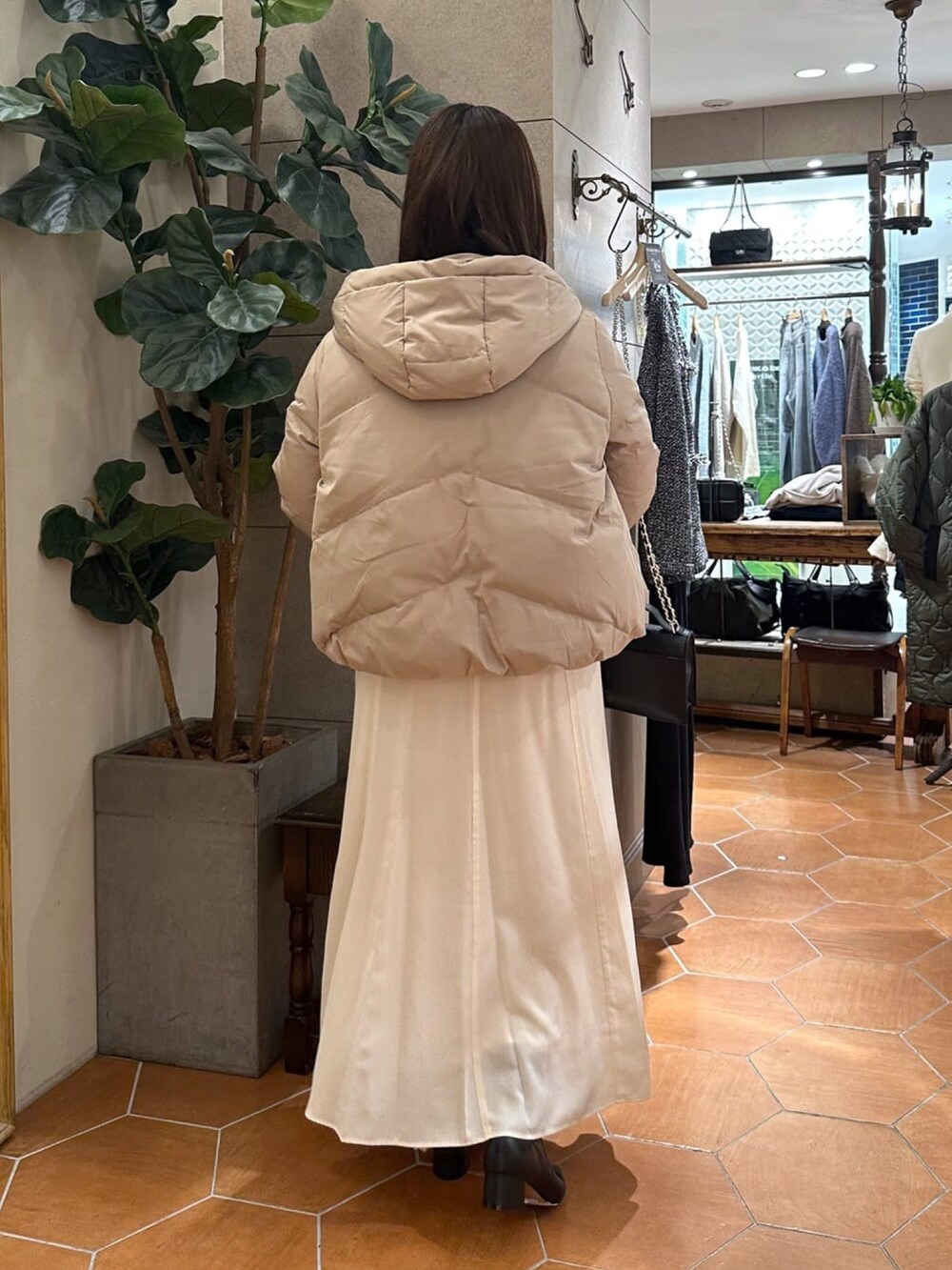 ブラック系のダウンジャケット/コート、ホワイト系のスカート、ブラック系のハンドバッグを着用したレディースの冬コーディネートの3枚目の写真