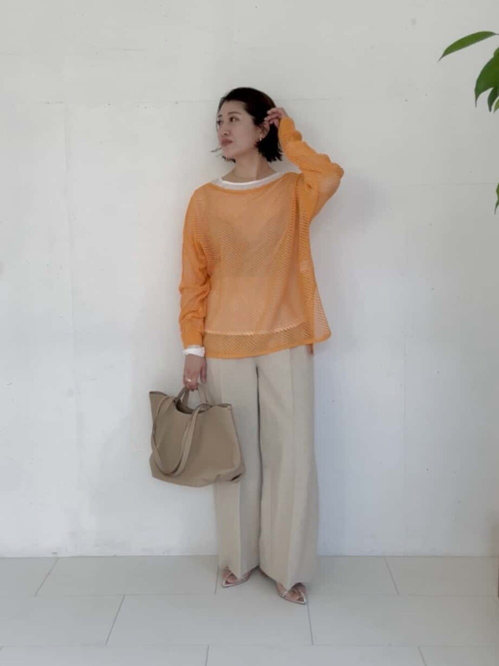 オレンジ系のニット/セーター、ベージュ系のその他パンツ、ベージュ系のトートバッグを着用したレディースの冬コーディネートの3枚目の写真