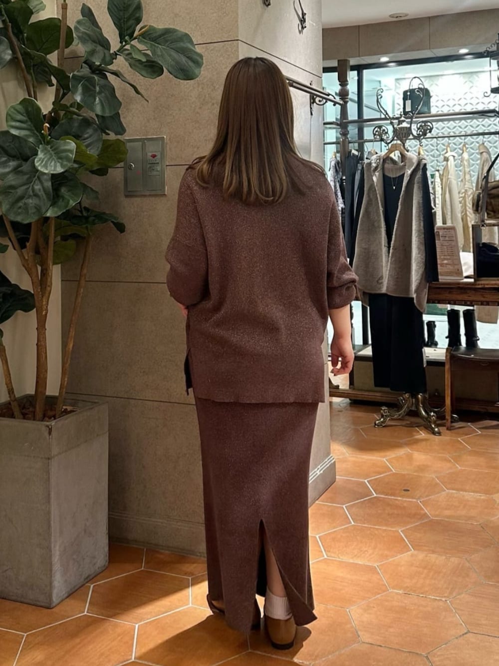 ブラウン系のニット/セーター、ブラウン系のスカート、イエロー系のローファーを着用したレディースの冬コーディネートの3枚目の写真