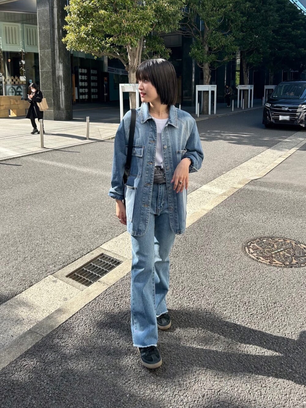 ブルー系のデニムジャケット、ブルー系のデニムパンツ、ブラック系のボディバッグ/ウエストポーチを着用したレディースの春コーディネートの2枚目の写真