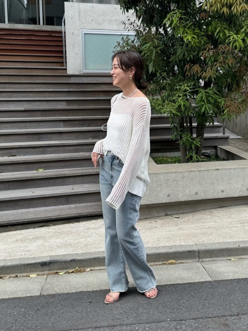 ホワイト系のニット/セーター、ブルー系のデニムパンツ、グレー系のサンダルを着用したレディースの春コーディネートの2枚目の写真