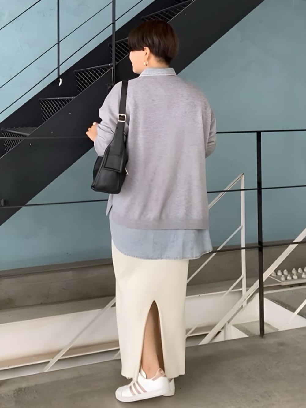 グレー系のニット/セーター、ブルー系のシャツ/ブラウス、ベージュ系のスカートを着用したレディースの秋コーディネートの2枚目の写真