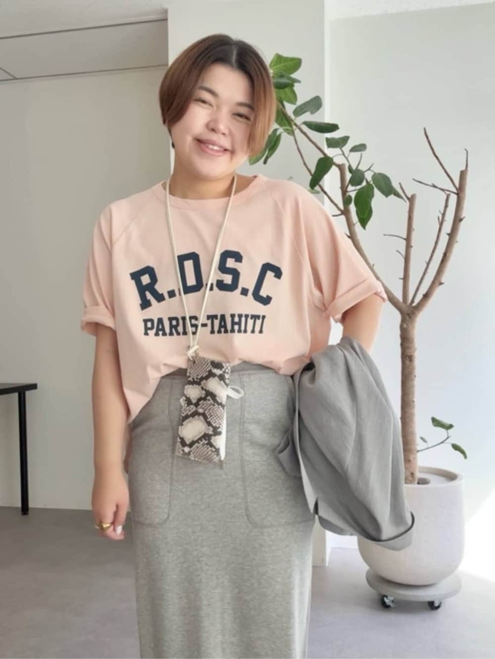 グレー系のスカート、ピンク系のTシャツ/カットソー、シルバー系のチョーカーを着用したレディースの春コーディネートの3枚目の写真