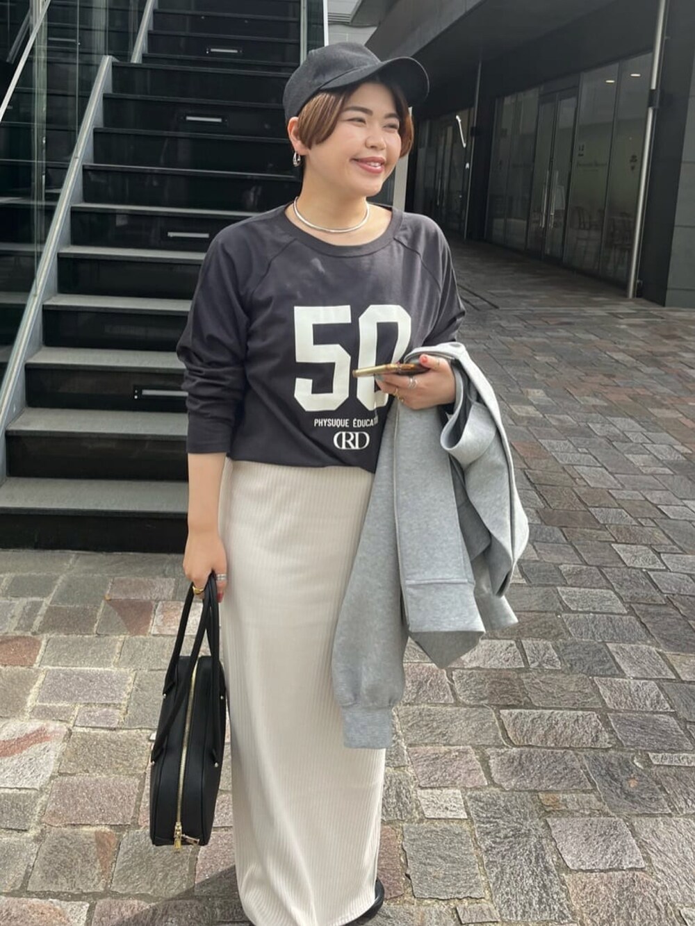 ホワイト系のスカート、ブラック系のサンダル、ブラック系のショルダーバッグを着用したレディースの夏コーディネートの2枚目の写真