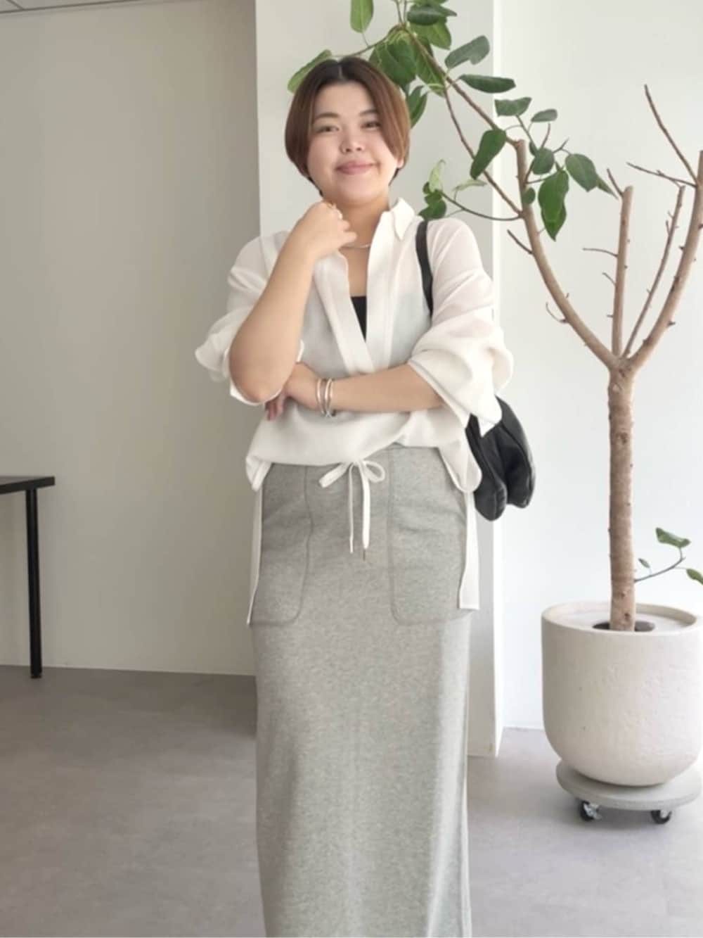 ブラック系のショルダーバッグ、グレー系のスカート、ホワイト系のシャツ/ブラウスを着用したレディースの春コーディネートの4枚目の写真