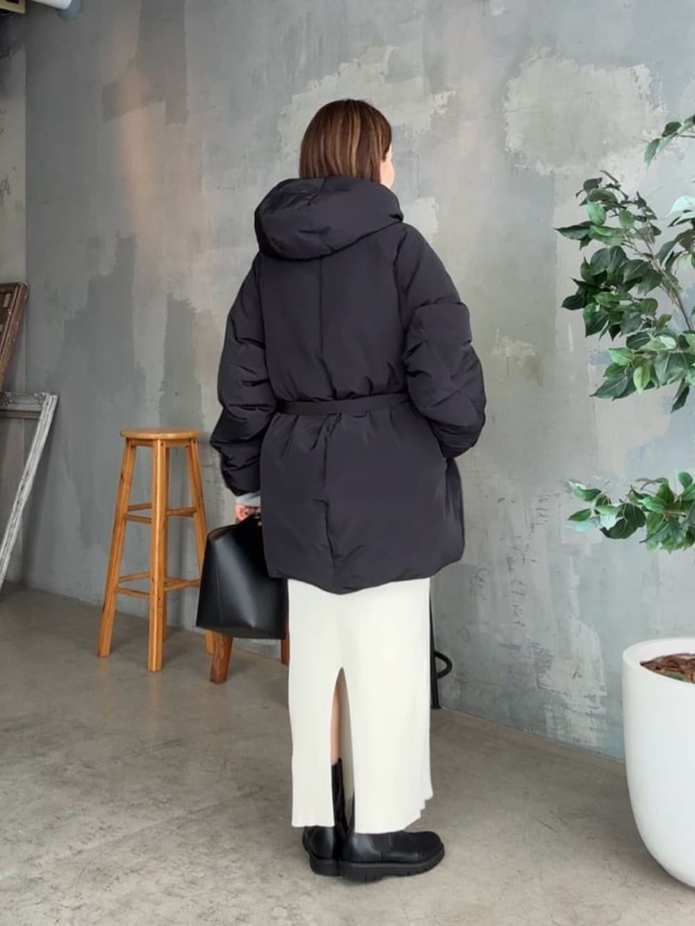 ブラック系のダウンジャケット/コート、ホワイト系のスカート、ブラック系のハンドバッグを着用したレディースの冬コーディネートの3枚目の写真