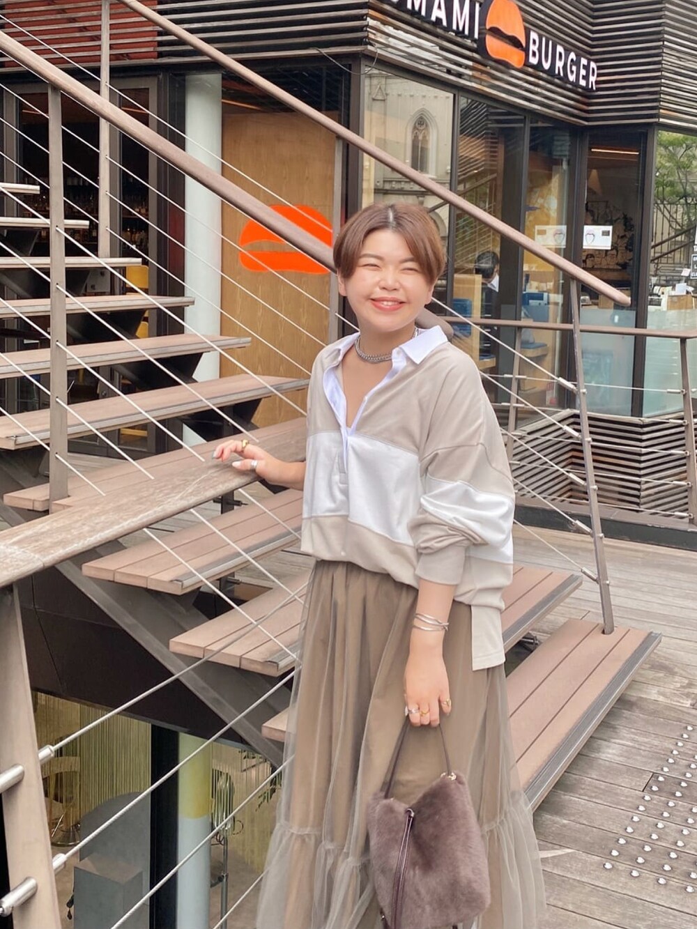 ベージュ系のTシャツ/カットソー、ブラウン系のスカート、ベージュ系のブーツを着用したレディースの夏コーディネートの3枚目の写真