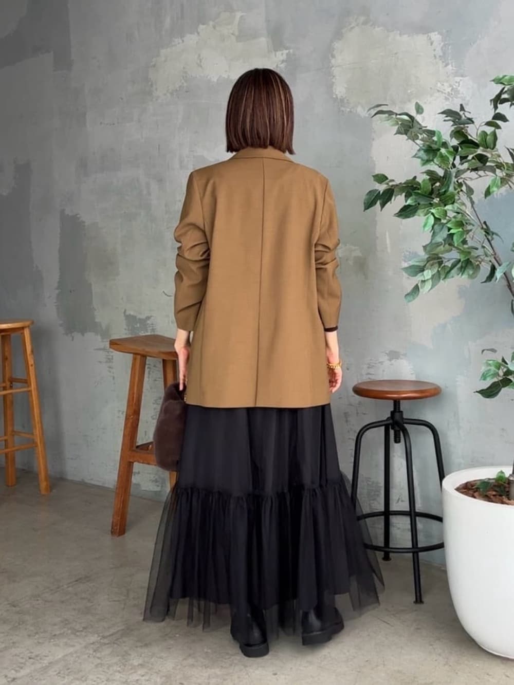 ブラウン系のテーラードジャケット、ブラウン系のTシャツ/カットソー、ブラック系のスカートを着用したレディースの秋コーディネートの3枚目の写真