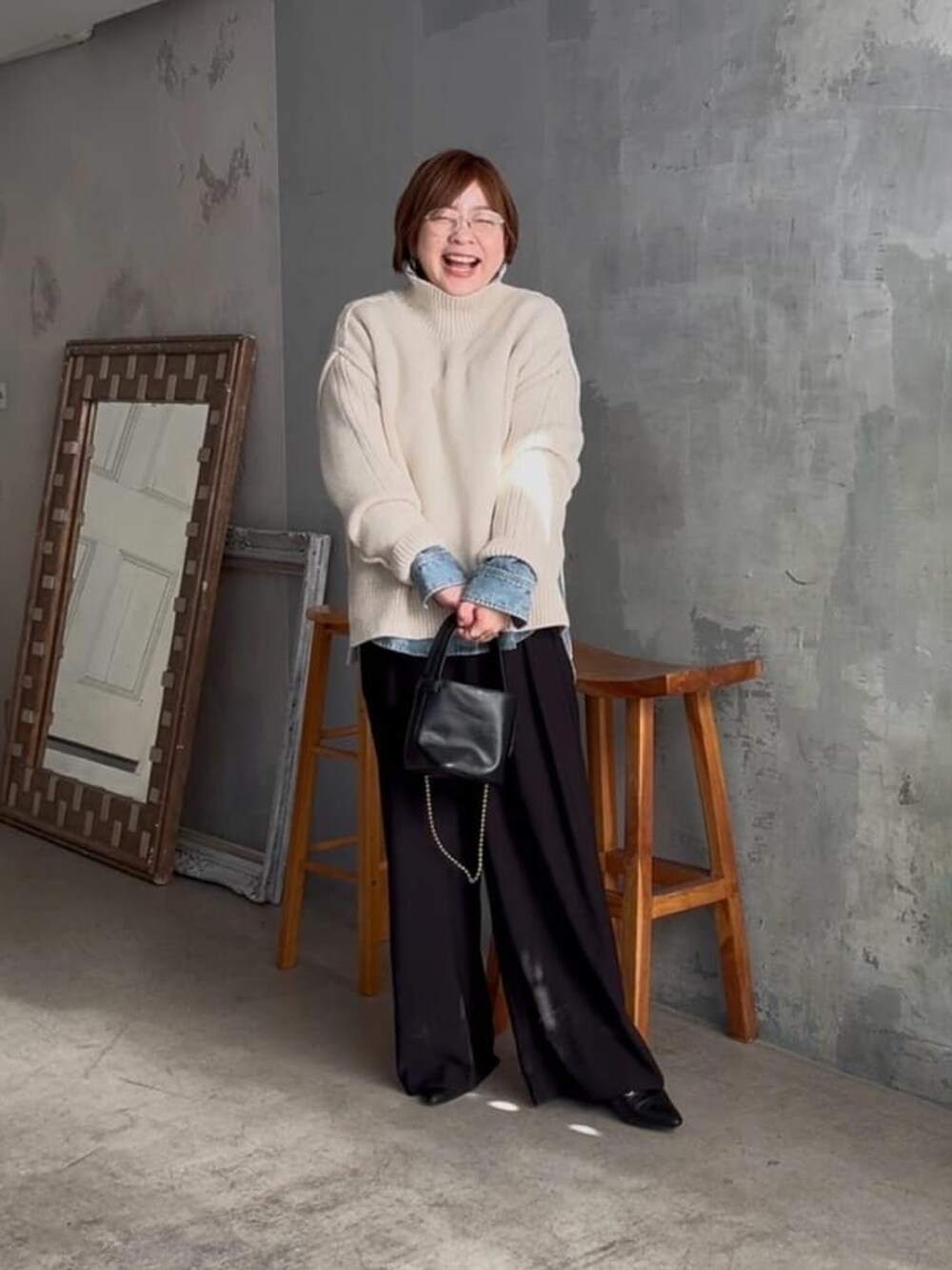 ホワイト系のニット/セーター、ブルー系のシャツ/ブラウス、ブラック系のスラックスを着用したレディースの冬コーディネートの2枚目の写真