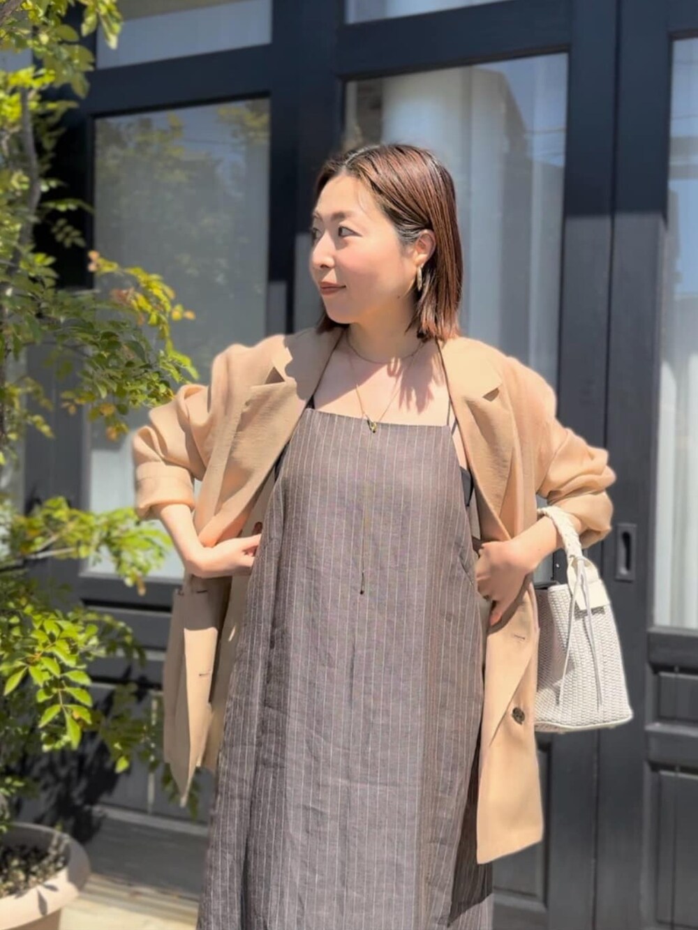 ブラック系のテーラードジャケット、ブラウン系のワンピース、シルバー系のサンダルを着用したレディースの春コーディネートの5枚目の写真