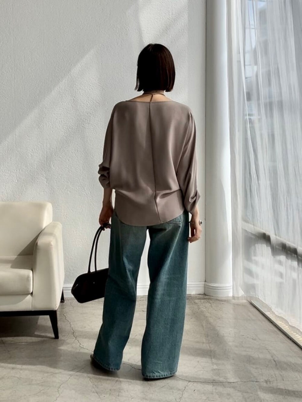 ブルー系のデニムパンツ、ブラウン系のショルダーバッグ、ブラウン系のローファーを着用したレディースの夏コーディネートの3枚目の写真