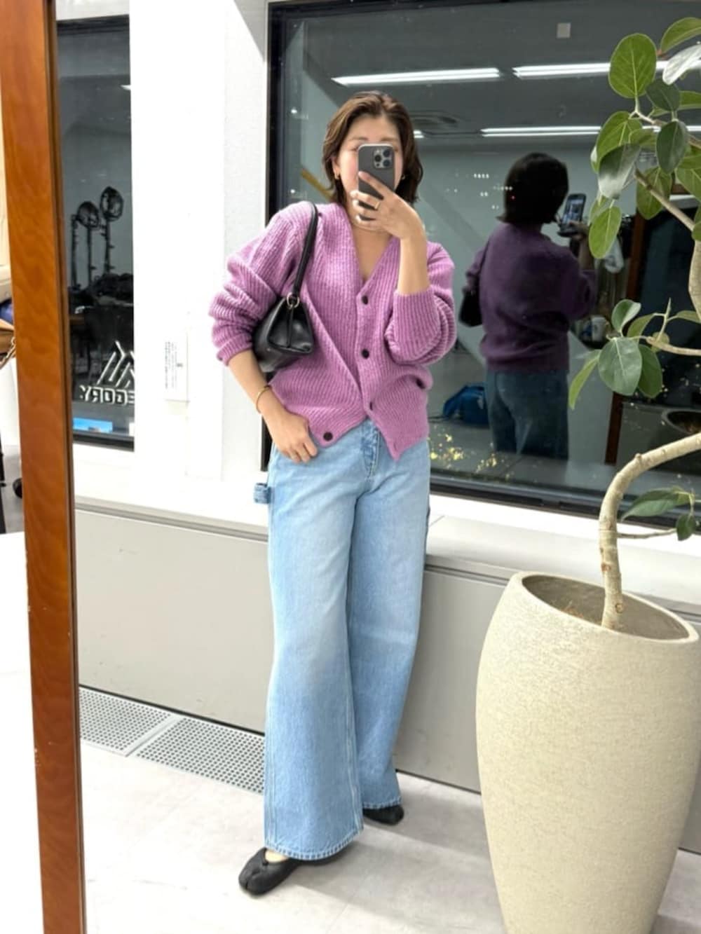 ブルー系のデニムパンツ、ブラック系のハンドバッグ、ピンク系のカーディガン/ボレロを着用したレディースの秋コーディネートの4枚目の写真