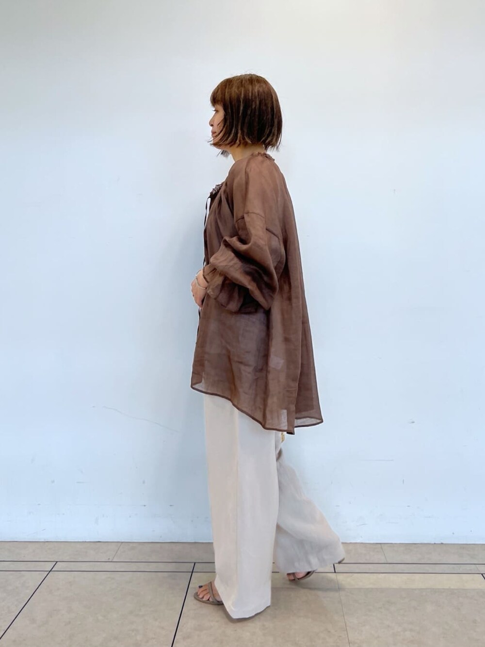 ブラウン系のシャツ/ブラウス、ベージュ系のパンツ、ゴールド系のショルダーバッグを着用したレディースの春コーディネートの2枚目の写真