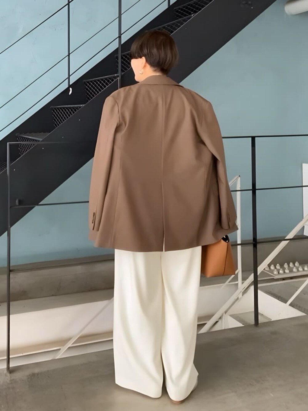 ブラウン系のテーラードジャケット、ベージュ系のニット/セーター、ホワイト系のスラックスを着用したレディースの秋コーディネートの3枚目の写真