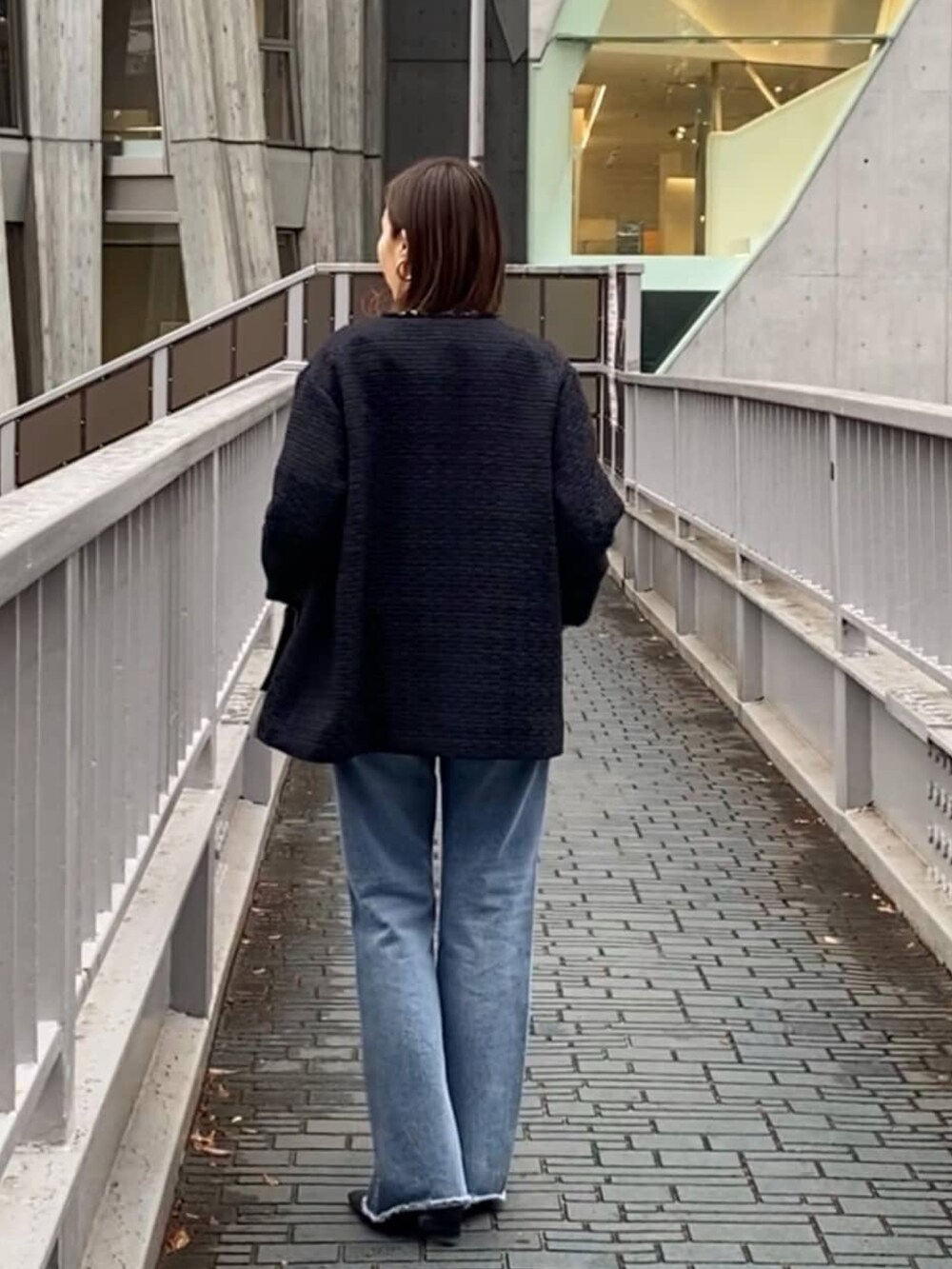 ホワイト系のニット/セーター、ブルー系のノーカラージャケット、ブラック系のハンドバッグを着用したレディースの冬コーディネートの3枚目の写真