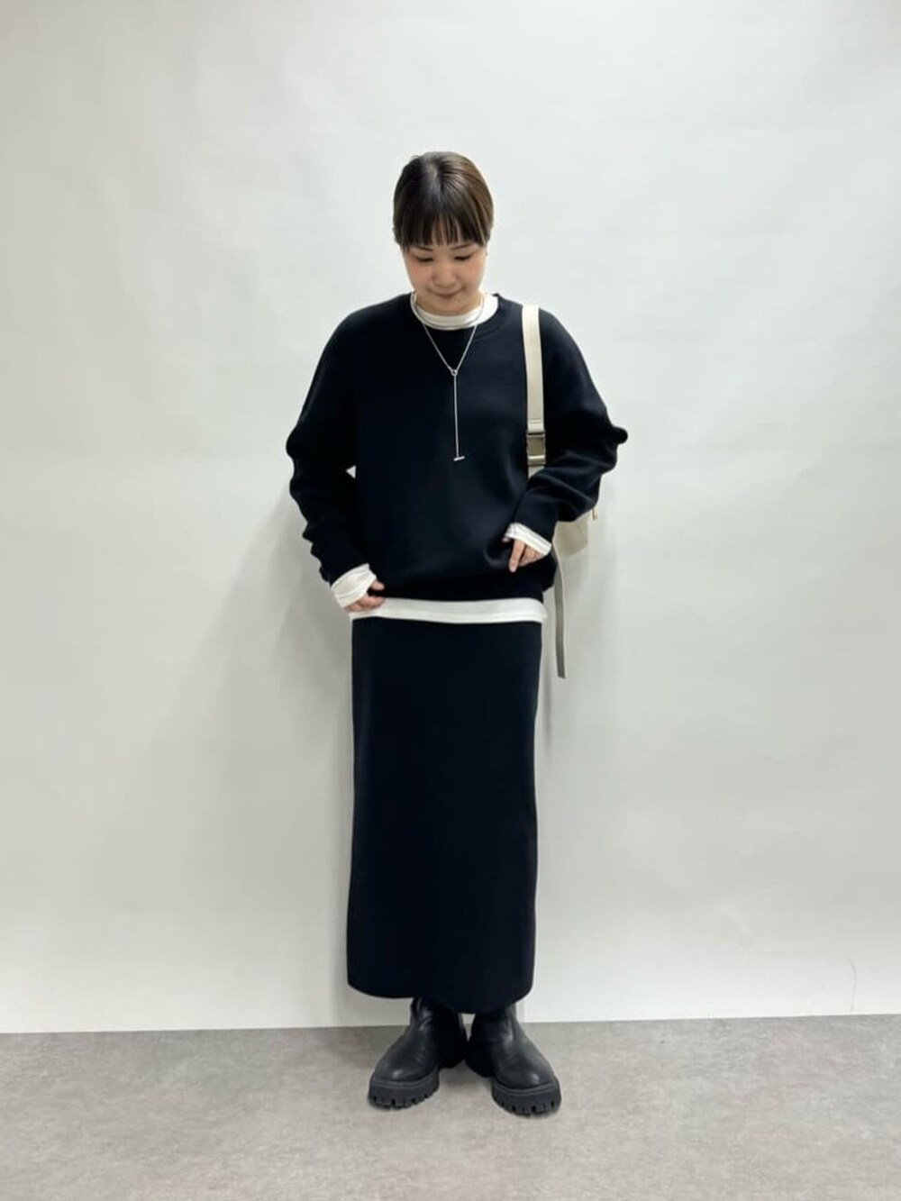 ホワイト系のボディバッグ/ウエストポーチ、ブルー系のニット/セーター、ホワイト系のTシャツ/カットソーを着用したレディースの冬コーディネートの2枚目の写真