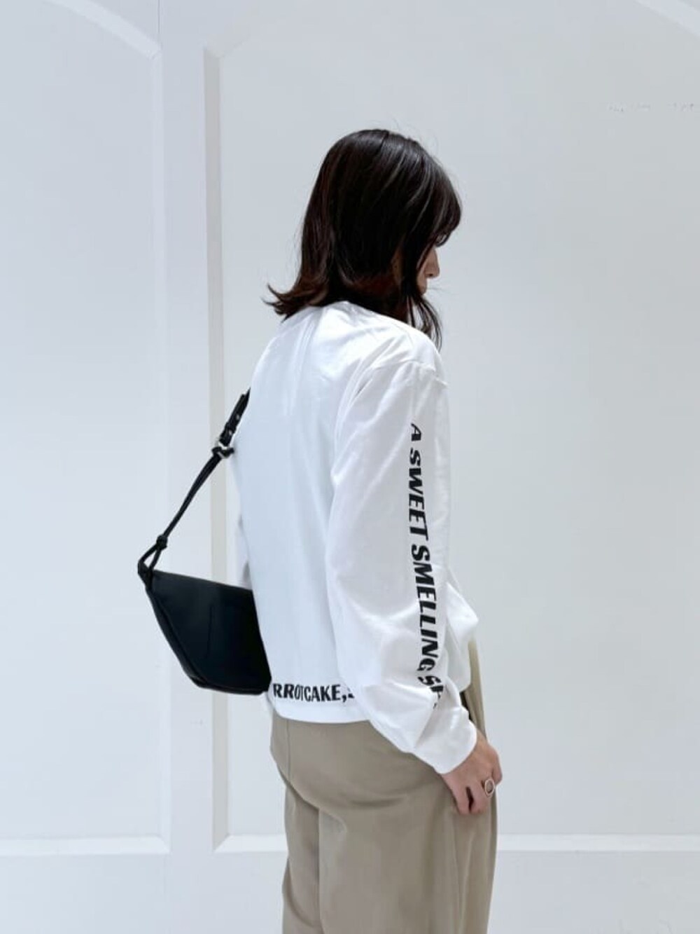 ベージュ系のチノパンツ、ホワイト系のTシャツ/カットソー、ブラック系のボディバッグ/ウエストポーチを着用したレディースの冬コーディネートの4枚目の写真