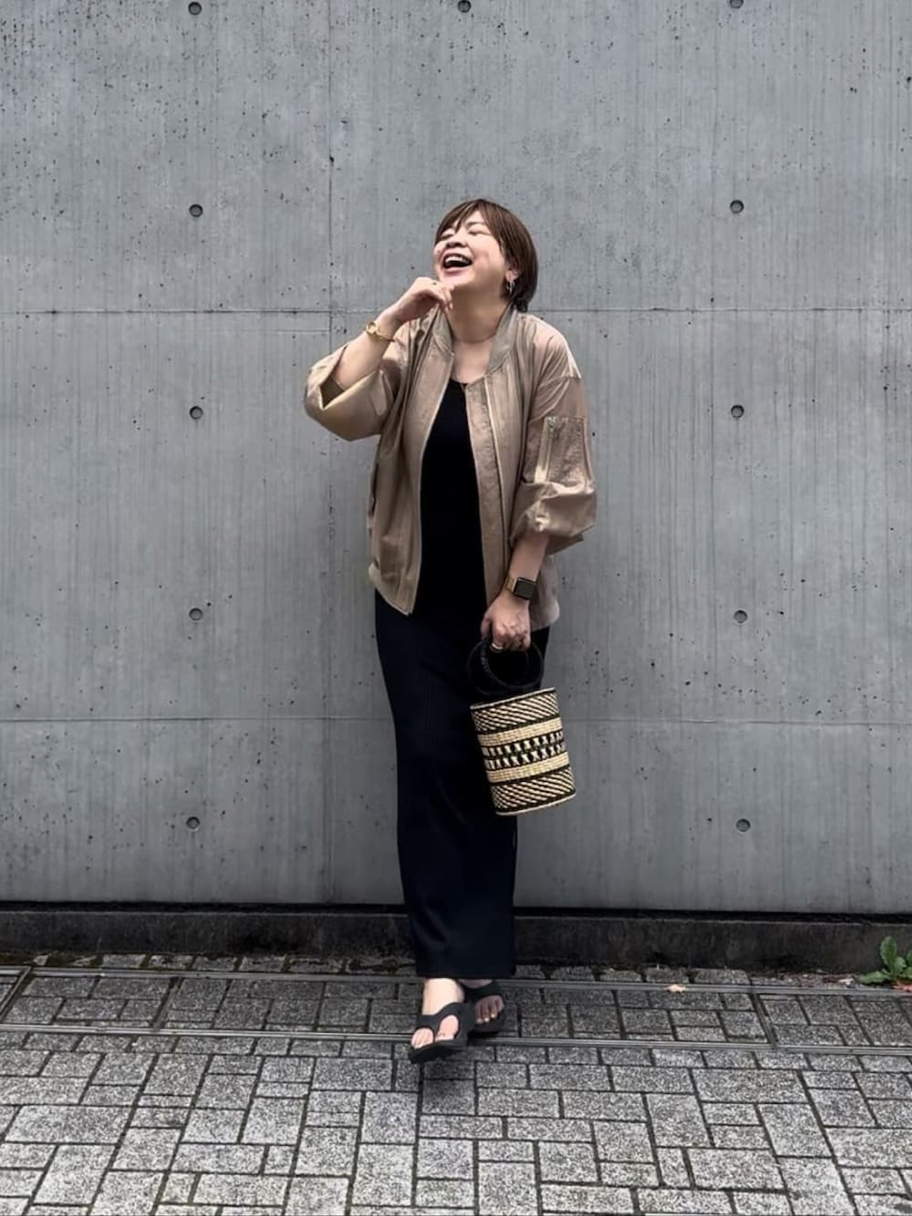 ベージュ系のブルゾン、ブラック系のワンピースを着用したレディースの夏コーディネートの3枚目の写真