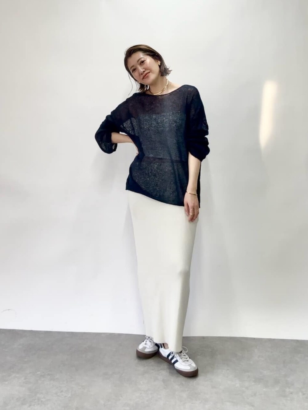 ブルー系のニット/セーター、ホワイト系のスカート、シルバー系のネックレスを着用したレディースの春コーディネートの3枚目の写真