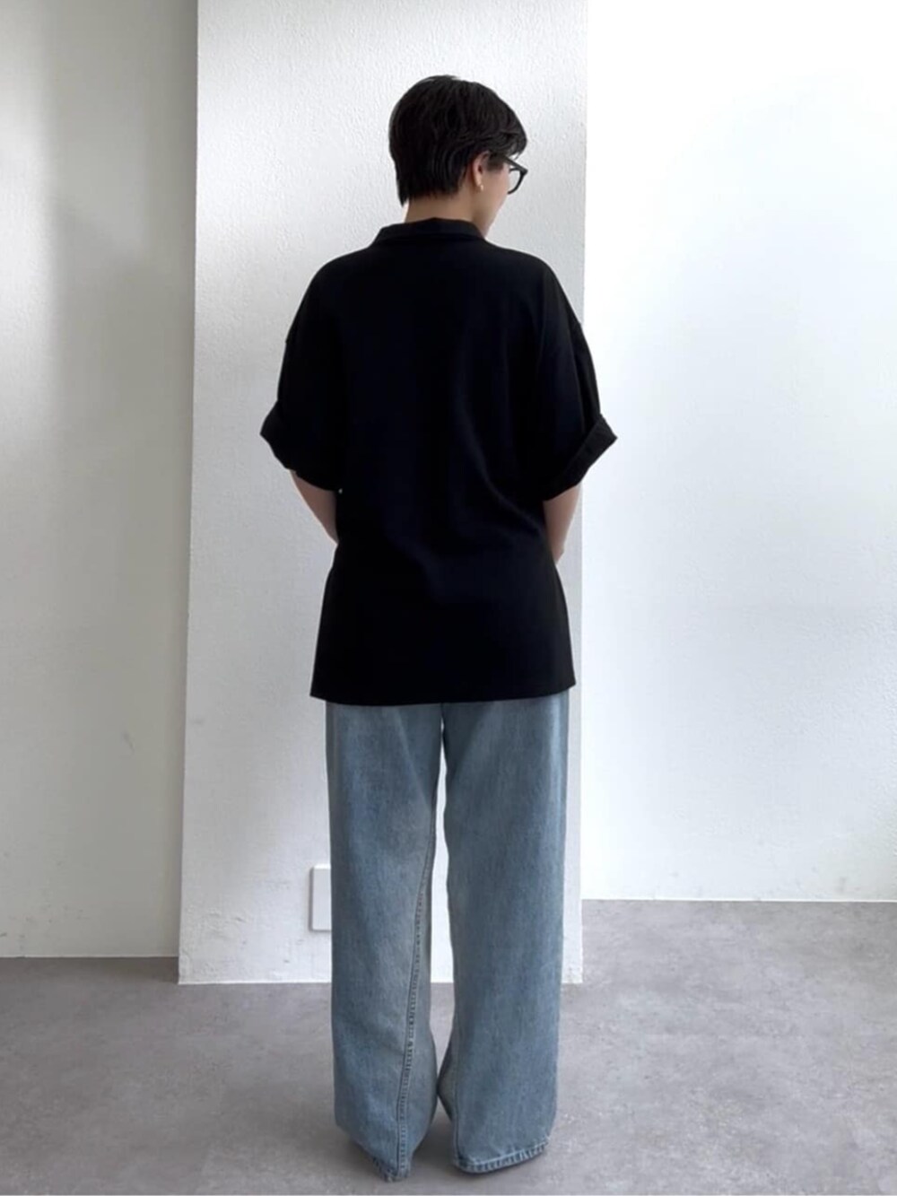 ブルー系のデニムパンツ、ブルー系のサンダル、ブラック系のポロシャツを着用したレディースの春コーディネートの4枚目の写真