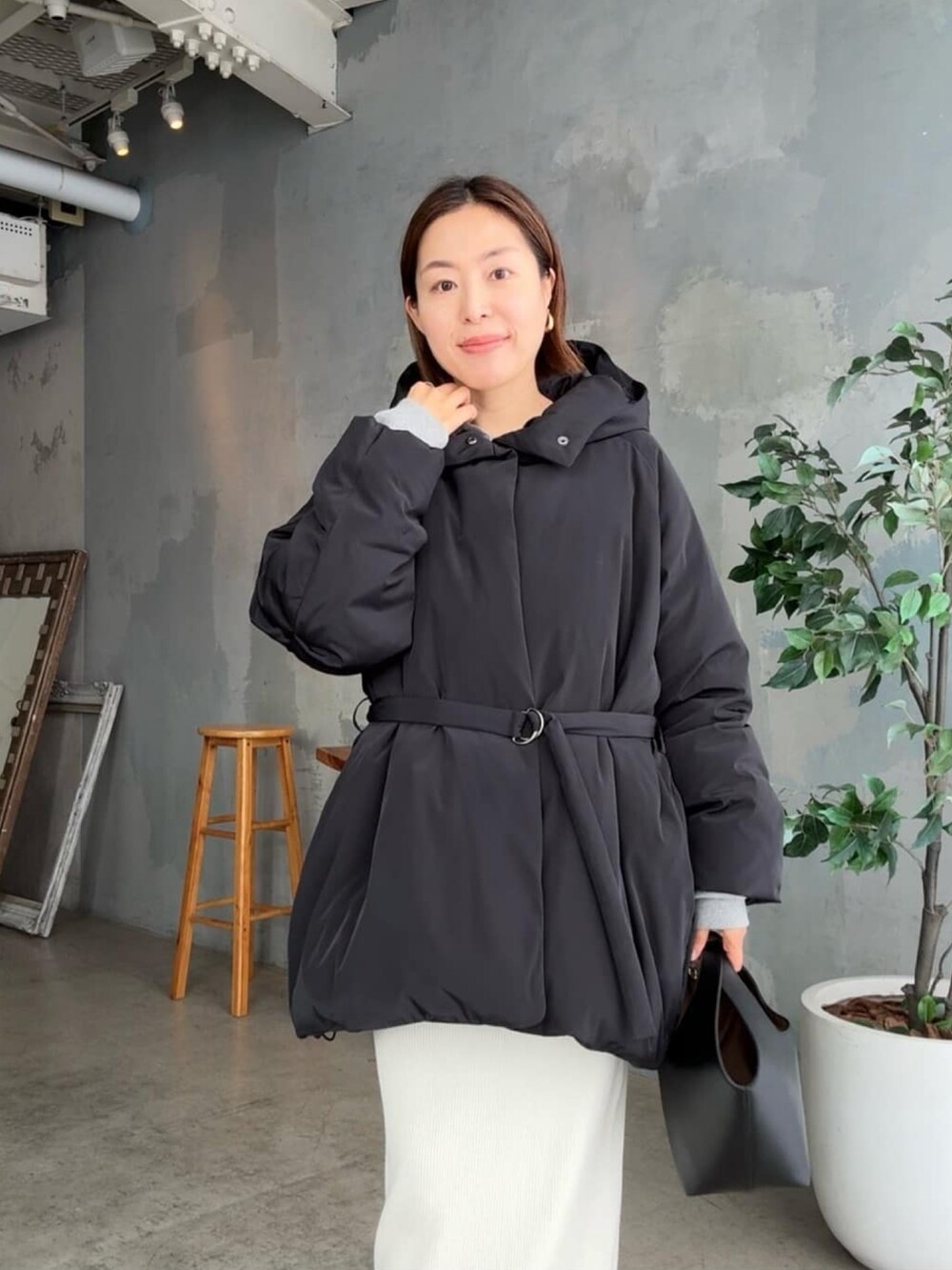 ブラック系のダウンジャケット/コート、ホワイト系のスカート、ブラック系のハンドバッグを着用したレディースの冬コーディネートの4枚目の写真